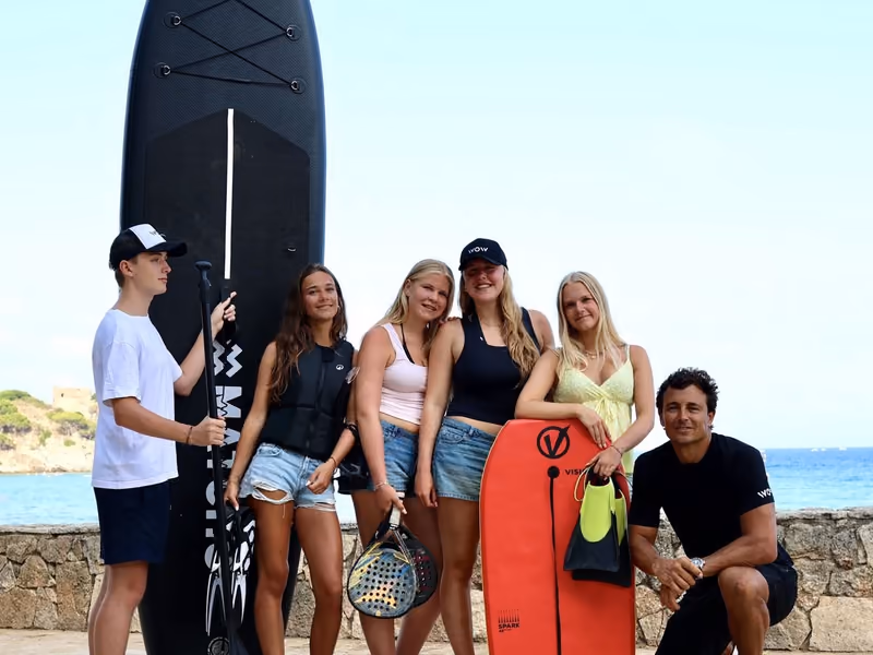 Leerlingen met SUP-board, padelrackets en bodyboard aan de kust van Palamós